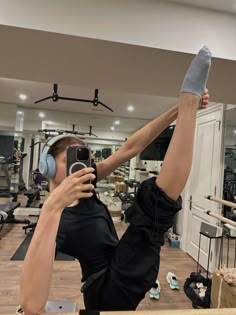 a woman wearing headphones and holding her leg up in the air with one hand