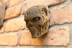 a brick wall with a carved mask on it's face hanging from the side