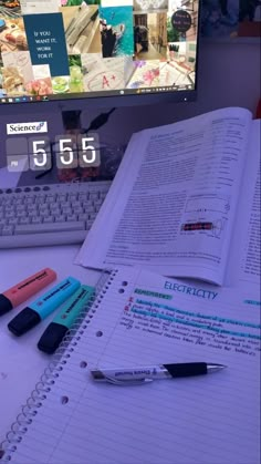 an open book sitting on top of a desk next to a keyboard and computer monitor