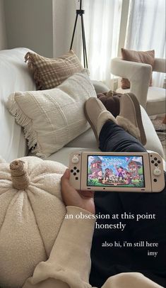 a person laying on top of a white couch holding a nintendo wii game controller in their hand