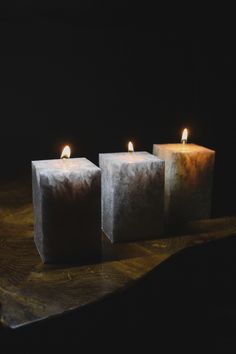 three lit candles sitting on top of a wooden table