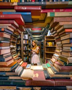 a woman standing in front of a large amount of books