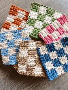 four crocheted dishcloths sitting on top of a wooden table