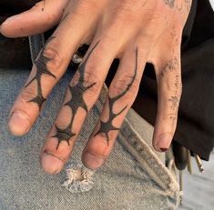 a man with tattoos on his hands and fingers is holding onto something that appears to be spider web