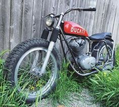 a red and black motorcycle parked next to a wooden fence