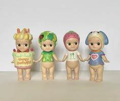 three little dolls holding hands in front of a white wall