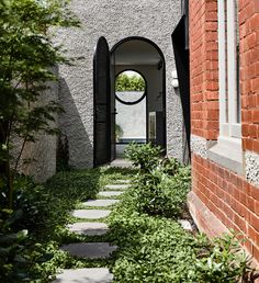 an archway between two buildings with plants growing on either side and walkway leading to it