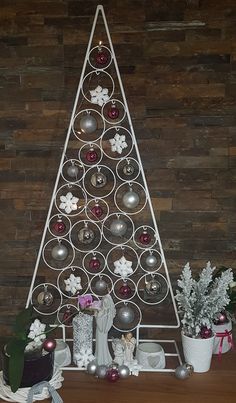 a christmas tree made out of metal circles with ornaments around it on a wooden table