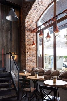 the interior of a restaurant with tables, chairs and stairs leading up to an open window