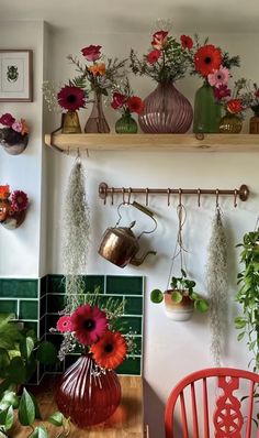 some flowers are hanging on the wall above a table with chairs and potted plants