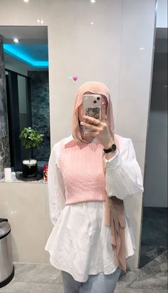 a woman taking a selfie in front of a mirror wearing a pink and white top