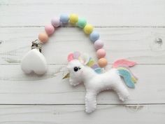 a white unicorn keychain with pastel colors on it and a pacifier