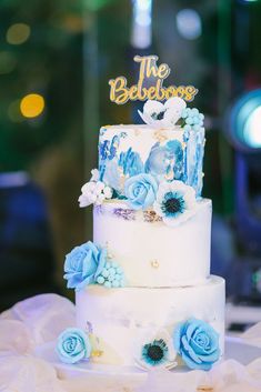 a three tiered cake with blue flowers and the words the belbodge on top