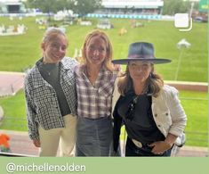 three women standing next to each other in front of a baseball field at a stadium