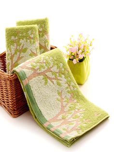 two green towels sitting next to a basket with flowers