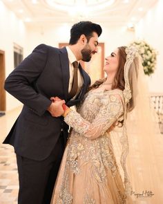 a bride and groom pose for a photo in their wedding dress at the reception venue