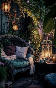 an outdoor seating area is lit up with candles and lanterns in the dark, surrounded by greenery