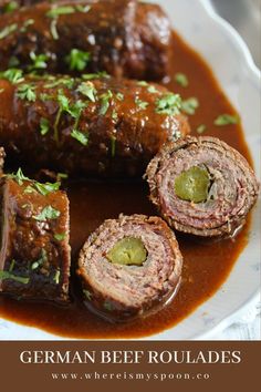 some meat rolls are on a plate with sauce and green garnish around them