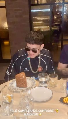 two young men sitting at a table with food and drinks in front of them,