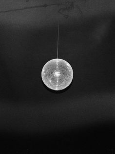 a black and white photo of a light fixture hanging from a wire in the dark