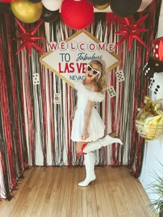 a woman standing in front of a welcome sign at a las vegas themed birthday party