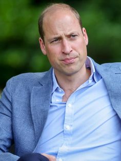 a man in a blue shirt and blazer sitting down