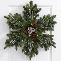 a christmas wreath on the front door with lights and pine cones hanging from it's center