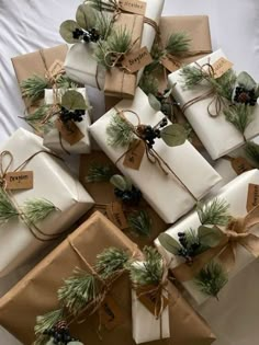 many wrapped presents are stacked on top of each other with pine cones and evergreen leaves