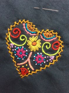 an embroidered piece of cloth with flowers and swirls on it