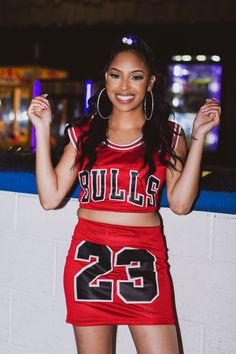 a woman in a cheerleader outfit holding a cell phone and posing for the camera