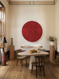 a dining room table with chairs and a large red circle on the wall above it