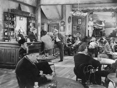 an old black and white photo of people sitting at tables