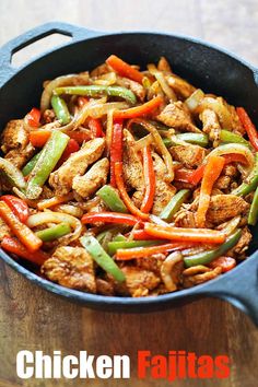 chicken fajitas with peppers and onions in a skillet on a wooden table