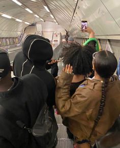 several people standing on an escalator with their cell phones up to their heads