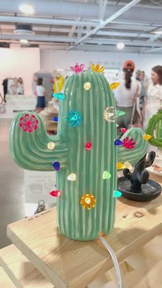 a green cactus sitting on top of a wooden table next to other items and people