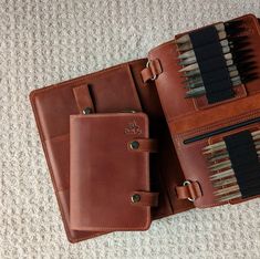 two brown leather cases with pens and pencils in them on the floor next to each other