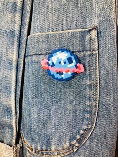 a lapel pin with an image of a pacman on it in the pocket of someone's jeans