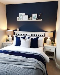 a bed with blue and white pillows in a bedroom next to two lamps on either side of the bed