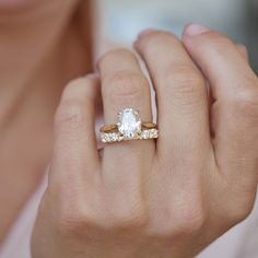 a close up of a person wearing a ring with an oval shaped diamond on it