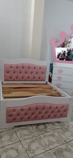 a pink and white bed frame in a room with tile flooring on the floor