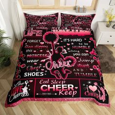 a bed with pink and black comforters on top of wooden floor next to plant