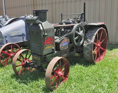 an old fashioned tractor sitting in the grass