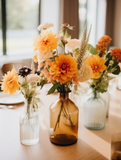 three vases filled with flowers sitting on top of a table