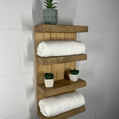 a wooden shelf with towels and potted plants on it