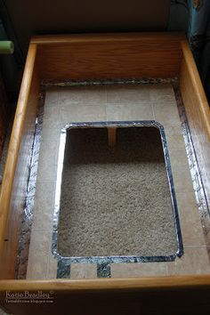 an open wooden box sitting on top of a tiled floor