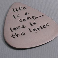 a guitar pick with the words life is a song love is the music on it