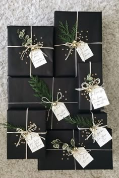 black wrapped presents tied with twine and green leaves are sitting on the floor next to each other