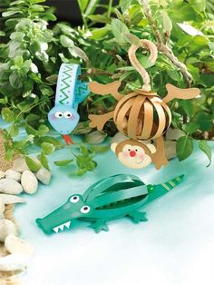 some paper animals are sitting on the ground in front of plants and rocks with leaves around them