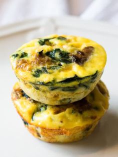 two muffins stacked on top of each other with spinach and cheese in the middle