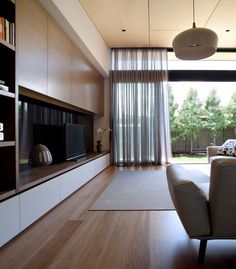 a modern living room with wood flooring and large sliding glass doors leading to the backyard